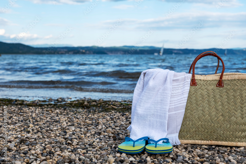 wicker basket, towel and slippers on a rocky beach against a beautiful sky wicker basket, towel and slippers on a rocky beach against a beautiful sky