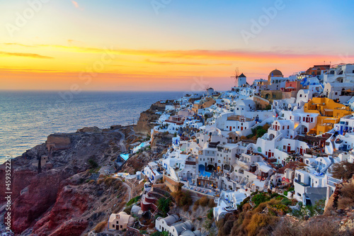 Greece vacation background. Famous iconic Oia village with traditional white houses and windmills during colorful sunset. Santorini island, Greece. © Nikolay N. Antonov