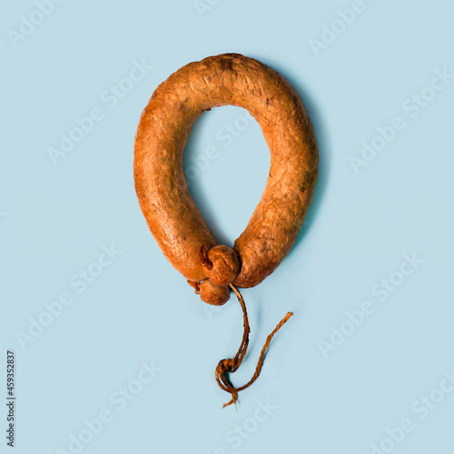 Beef sausage isolated on light blue background. Sausage in the form of a balloon