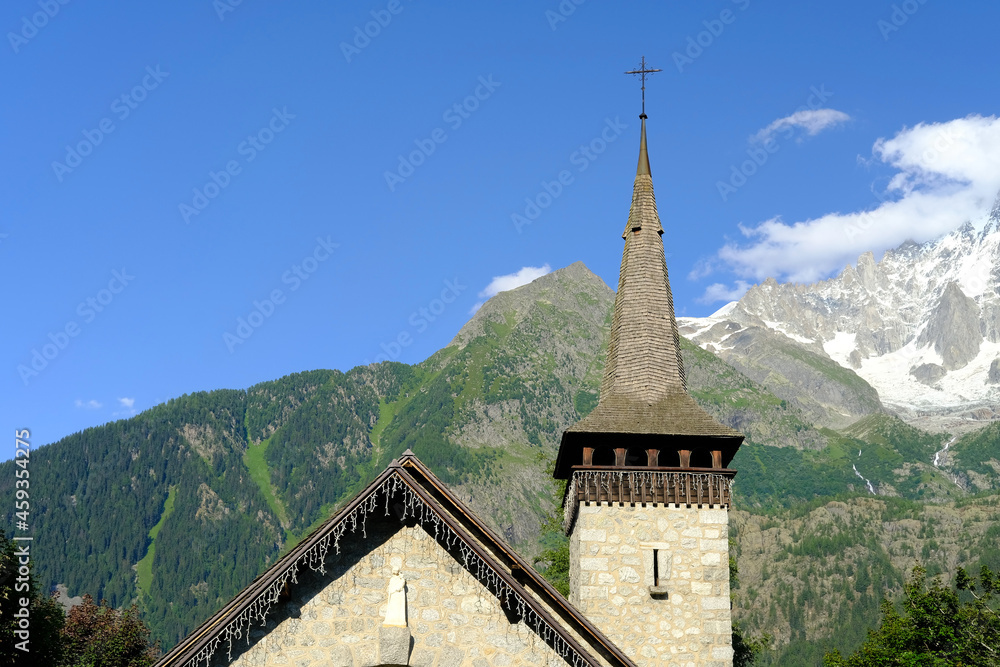 old little Les Praz Church in Chamonix-Mont-Blanc, building among green trees and high mountains, concept of travel, religion, mountain climbing