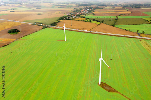 Wind turbine generating electricity, windmills against the background of a green field, an alternative source of energy, view from a drone