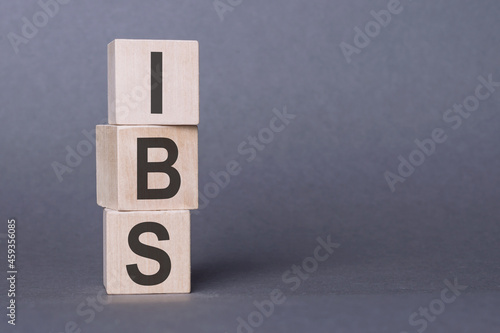 IBS - Irritable Bowel Syndrome, text written on wooden blocks, on gray background.