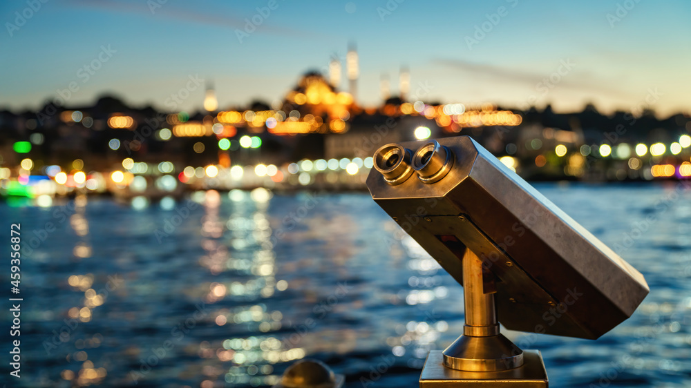 Touristic binoculars at Galata Bridge with Istanbul cityscape background at night. Observation deck for tourists to watch Istanbul's historic center, old town Eminonu