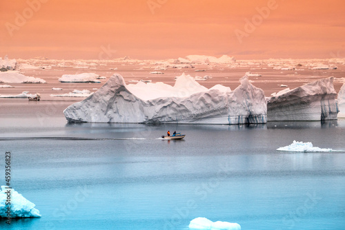fisherman boat bewtween arctic icebergs in greenland