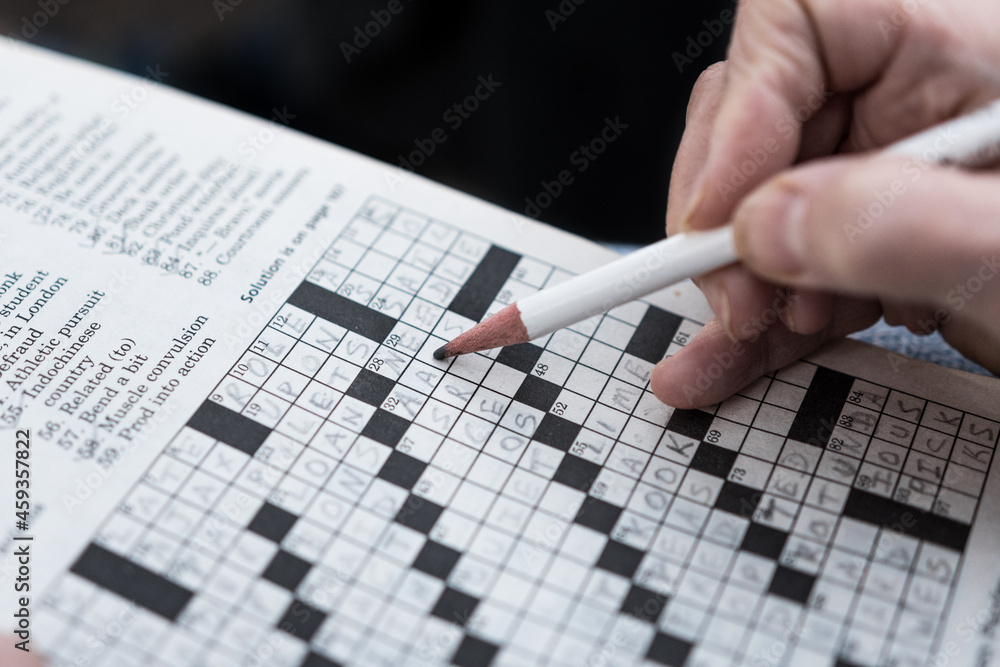 Solving a crossword puzzle in the newspaper close up hand background