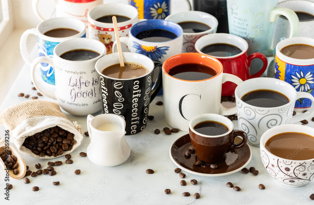 A table of many cups of coffee with selective focus on the word coffee on the black cup in front. A table of many cups of coffee with selective focus on the word coffee on the black cup in front.