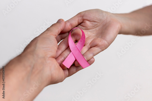 woman hand with pink ribbon and man hand supporting. pink October. breast cancer awareness campaign. selective focus
