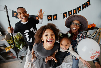 POV shot of excited African-American kids wearing Halloween costumes at home and looking at camera