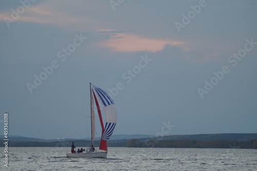 Full-color horizontal photo. A sports sailing vessel participates in a race in bad weather. Colored sails on the background of a stormy sky. photo