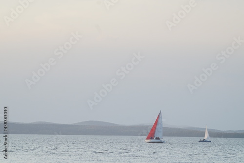 Full-color horizontal photo. A sports sailing vessel participates in a race in bad weather. Colored sails on the background of a stormy sky. photo