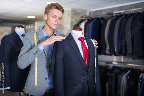 Adult male in shirt measuring business clothes jacket in the store photo