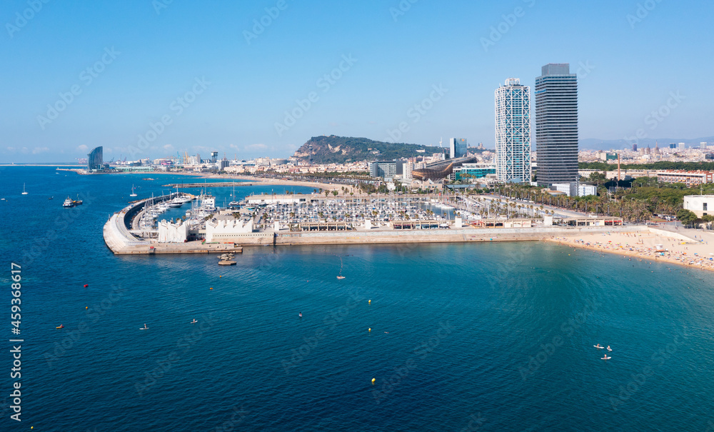 Aerial panoramic view of modern Barcelona cityscape on Mediterranean coast overlooking famous marina Olympic Harbour on sunny summer day, Spain