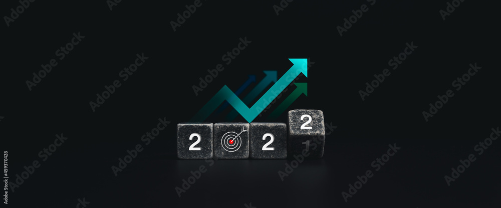 2022 Happy New year and successful concept banner with white 2022 year numbers on flipping black dice blocks with goal target icon symbol and uprising arrows on dark background, minimal style. 2022 Happy New year and successful concept banner with white 2022 year numbers on flipping black dice blocks with goal target icon symbol and uprising arrows on dark background, minimal style.