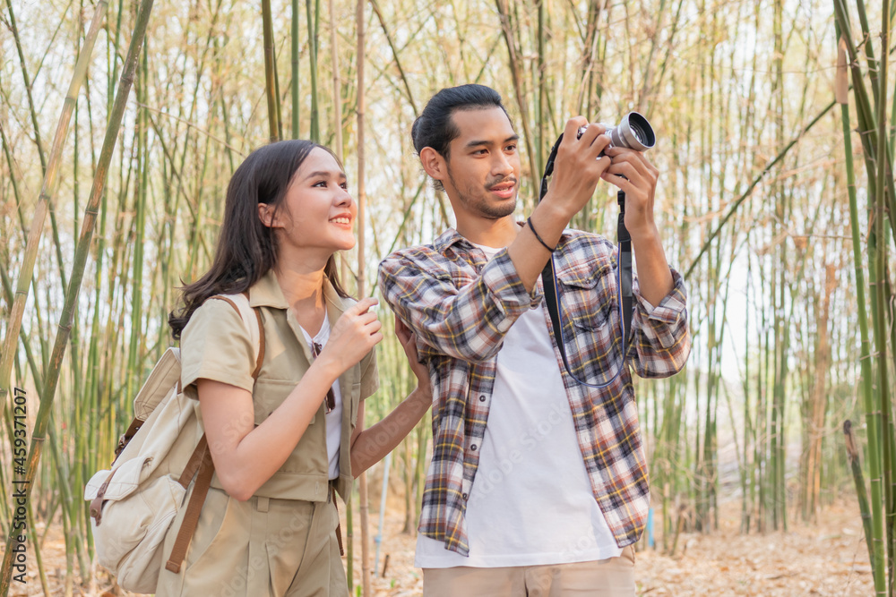 Beautiful, Happy asian young man,woman smile and look at camera after boyfriend take photo, picture of her while traveling together at forest, nation park. Summer vacation outdoor with couple concept.