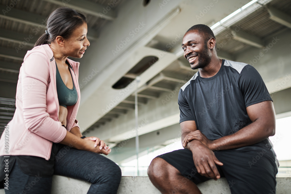 African young woman discussing sport training with her instructor while they sitting in the gym African young woman discussing sport training with her instructor while they sitting in the gym