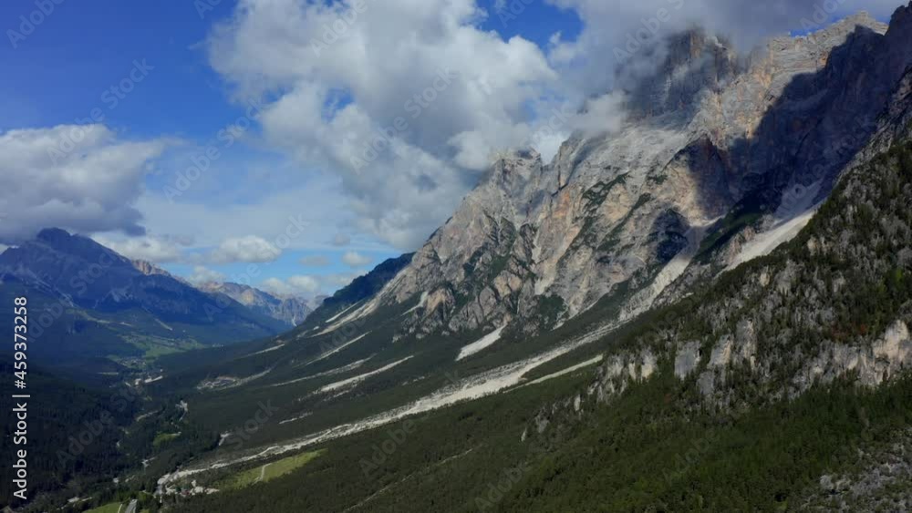 Dolomites, Cortina d'Ampezzo, Veneto, Italy, September 2021. Drone gradually ascends over woodland facing mountains touching the clouds. Dolomites, Cortina d'Ampezzo, Veneto, Italy, September 2021. Drone gradually ascends over woodland facing mountains touching the clouds.