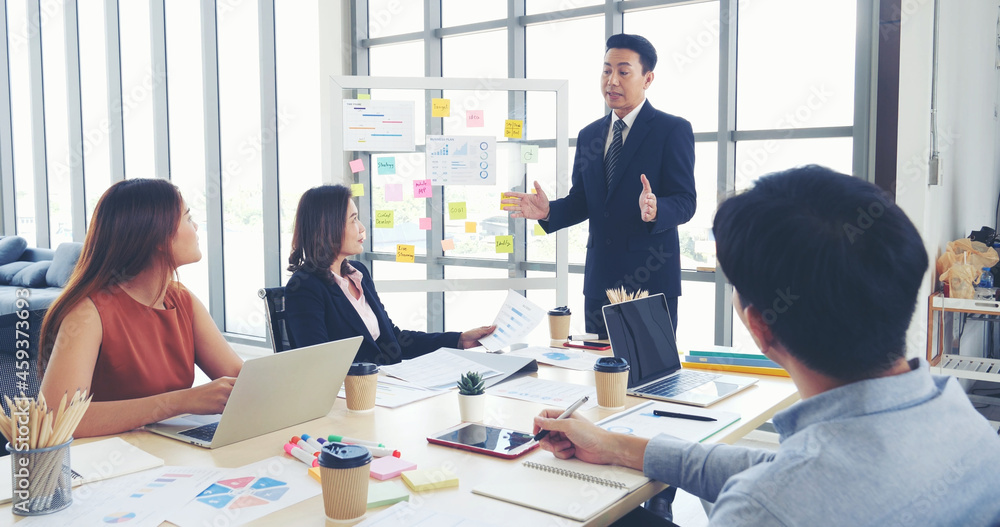 Fototapeta premium Happy business people meeting present graph chart investment, business data in meeting room. Group of business people meeting in conference room. Asian businessman speech, present teamwork partnership