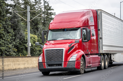 Wallpaper Mural Red bonnet big rig semi truck transporting frozen food cargo in refrigerator semi trailer with aerodynamic skirt driving on the highway road with green trees on the side Torontodigital.ca
