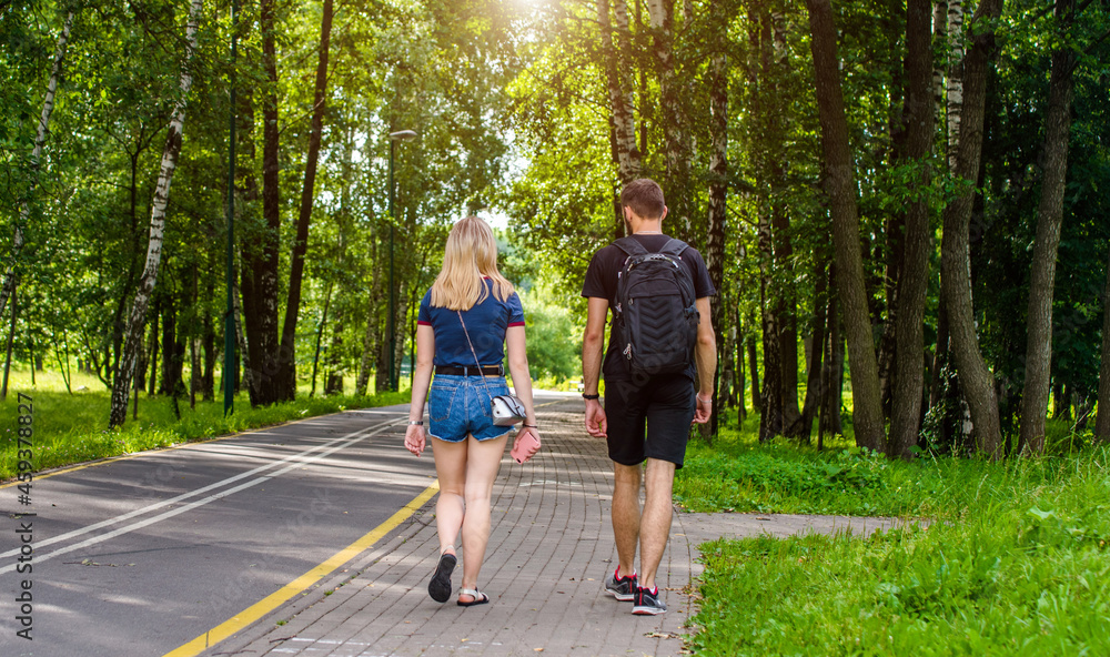 Fototapeta premium A guy and a girl walk along the path in the city Park