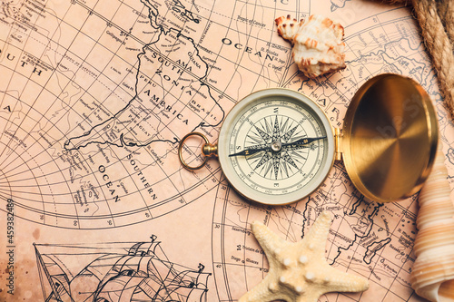 Old compass with sea shells on vintage world map
