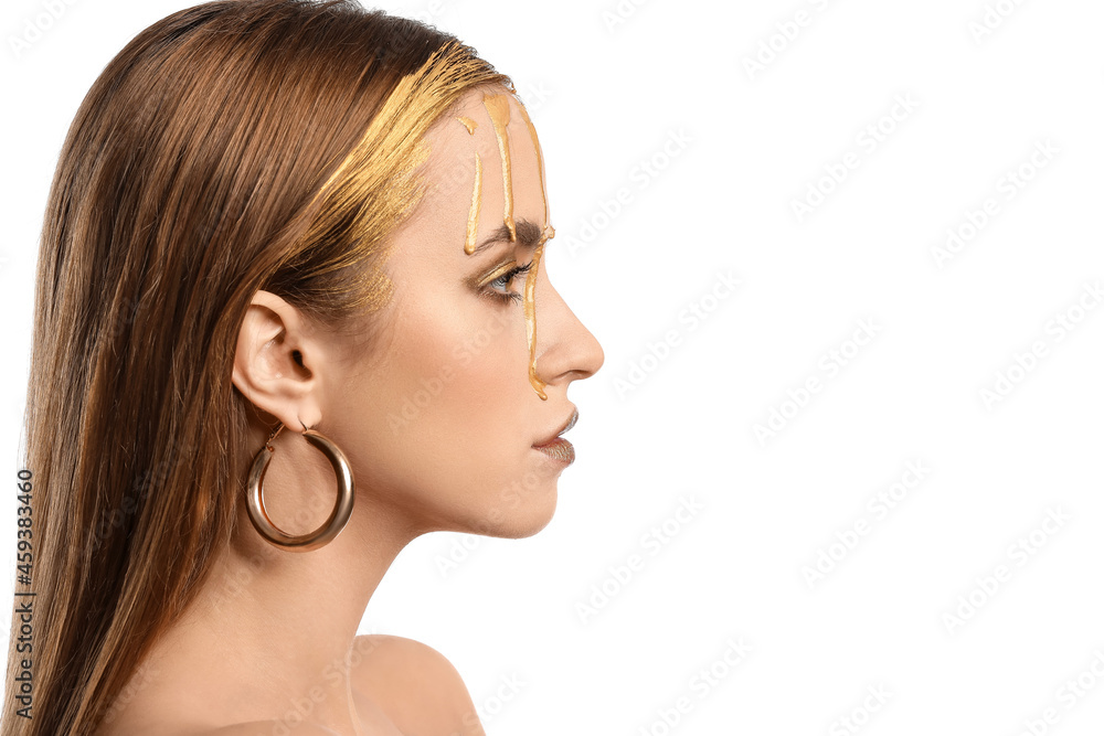 Beautiful young woman with golden paint on her face against white background Beautiful young woman with golden paint on her face against white background