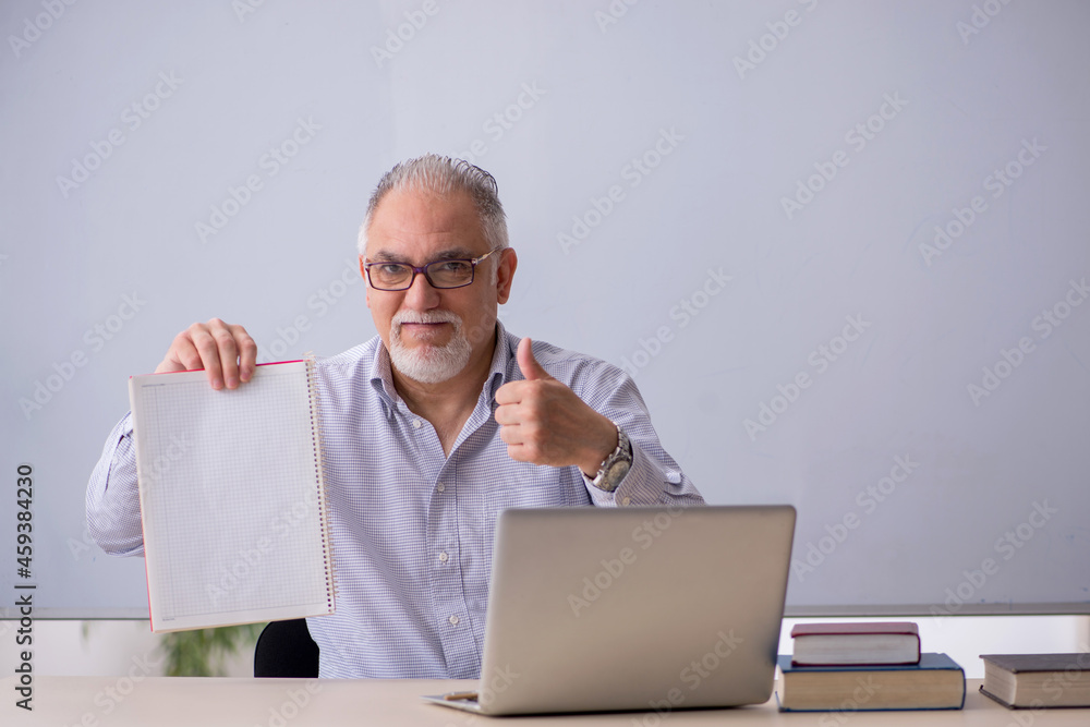 Old male teacher in front of whiteboard Old male teacher in front of whiteboard