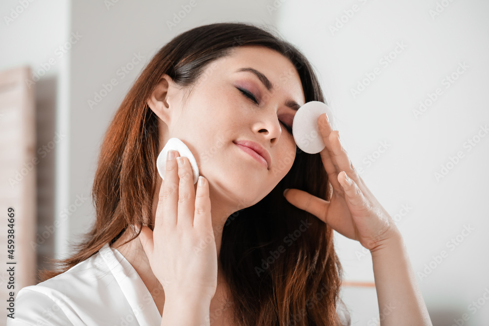 Beautiful young Asian woman removing makeup at home Beautiful young Asian woman removing makeup at home