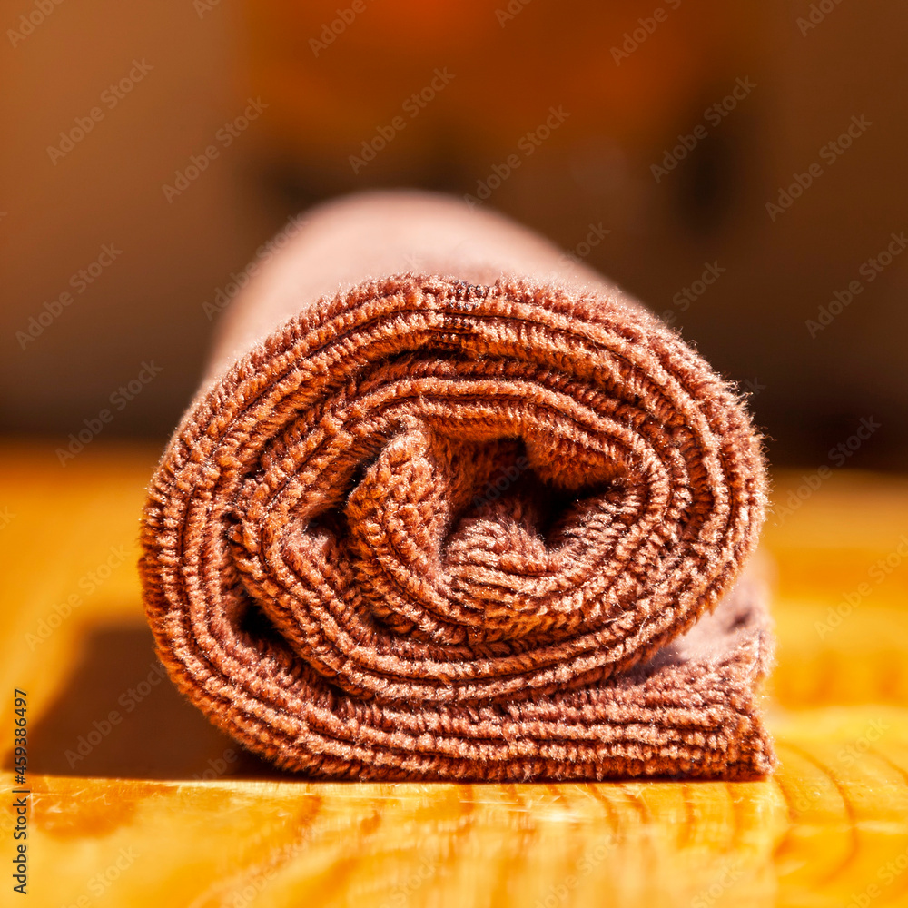 Brown three-ply microfibre tea towel rolled up on a wooden surface Brown three-ply microfibre tea towel rolled up on a wooden surface