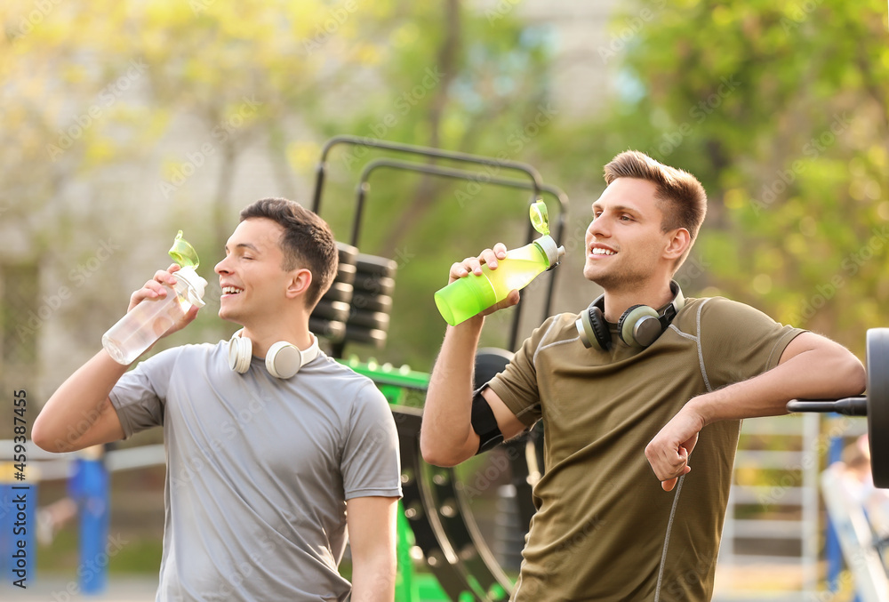 Obraz premium Young men drinking water on sport ground