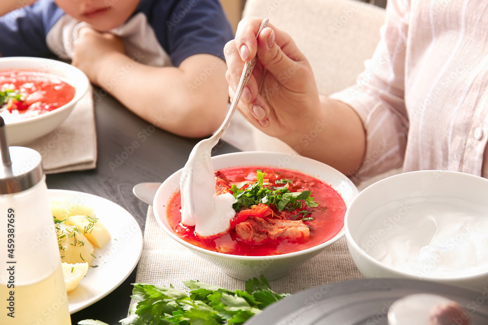 Woman eating delicious borscht with sour cream, closeup