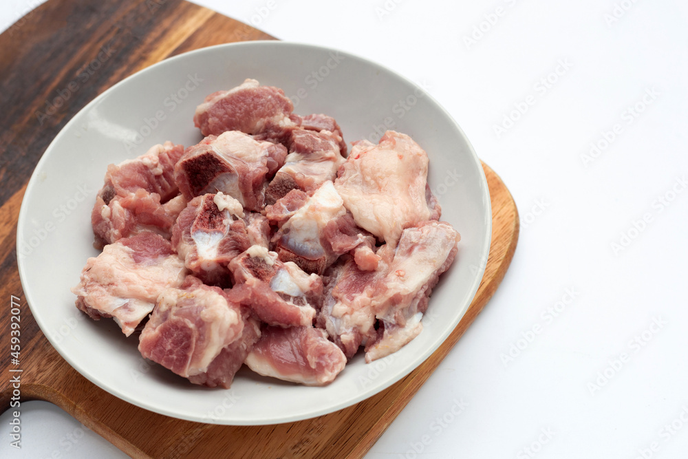 Raw pork ribs in white plate on cutting board on white background.