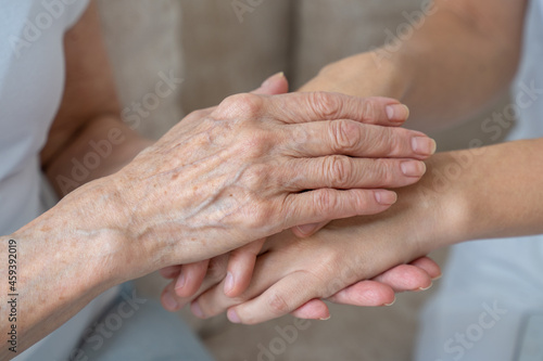 An elderly mother calms her daughter, strokes her, holds her hand in close-up