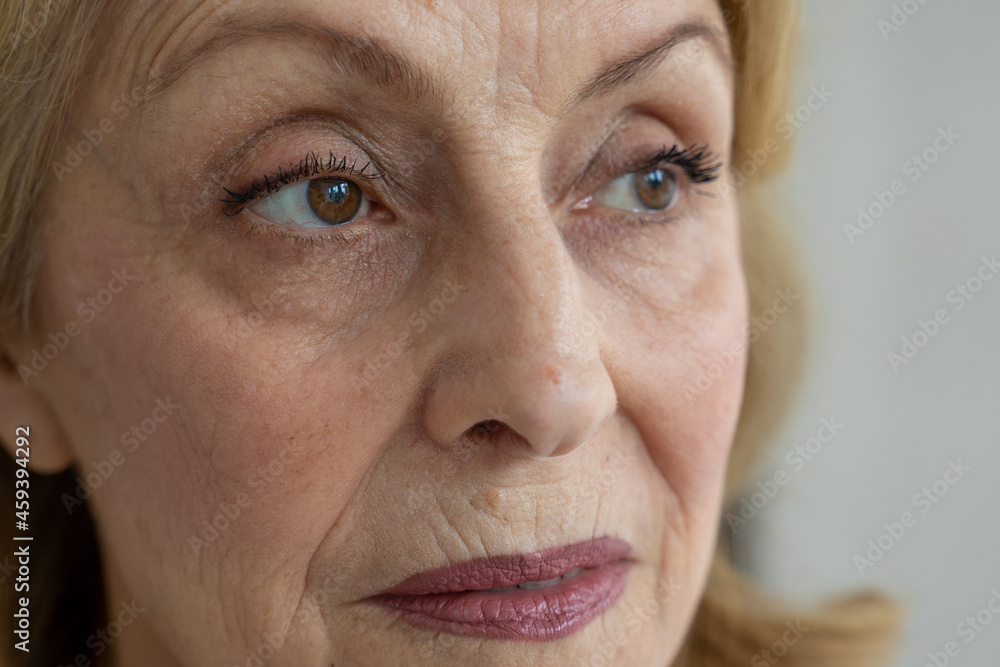 Sad brown eyes of an elderly woman looking away, taken close-up