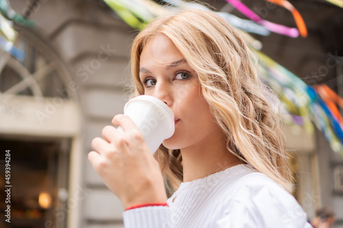 Close-up photo of a beautiful young woman holding a takeaway coffee cup.