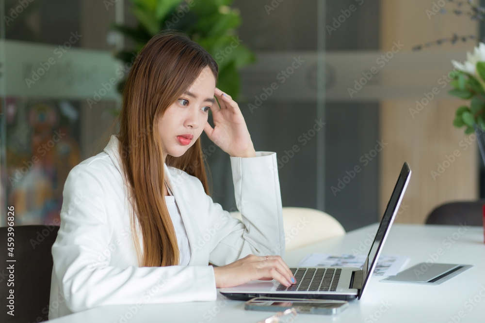 Asian business female working in co-working space with laptop paper work (Business woman concept.) Asian business female working in co-working space with laptop paper work (Business woman concept.)
