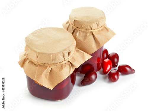 Jars of delicious dogwood jam and berries on white background