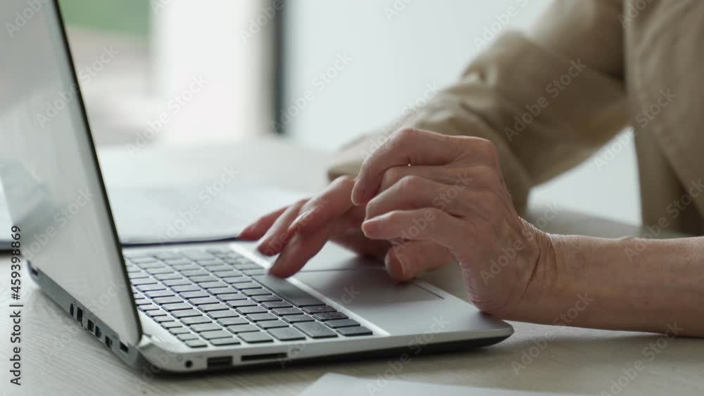 The hands of an elderly woman on the keyboard, a grandmother at a laptop at home The hands of an elderly woman on the keyboard, a grandmother at a laptop at home