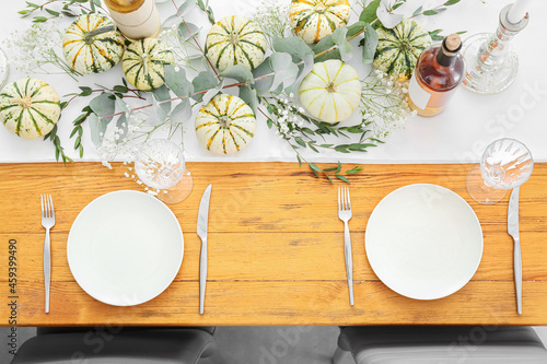 Festively served wooden table with bottle of wine and autumn decor in restaurant