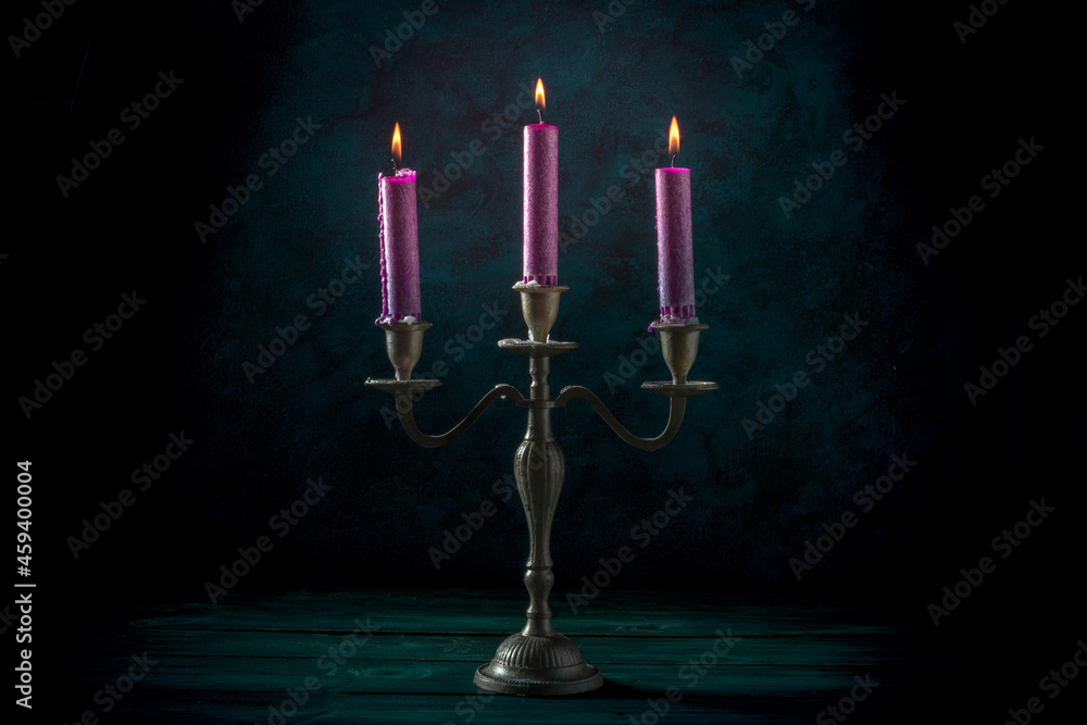 Fototapeta premium Burning candles in a vintage candle holder on a dark background