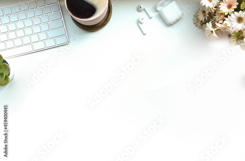 Coffee cup, earphones and keyboard on white office desk. Top view.