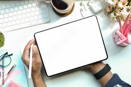 Overhead view creative man holding stylus pen and working with digital tablet on white table.