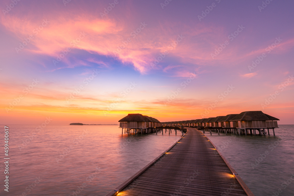 Maldives island sunset. Water bungalows resort at islands beach. Indian Ocean, Maldives. Beautiful sunset landscape, luxury resort and colorful sky. Artistic beach sunset under wonderful sky

