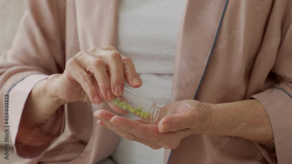 Woman's hand is holding a medicine in close-up, an elderly woman is holding a pill in her hands, pouring pills out of a bottle. Woman's hand is holding a medicine in close-up, an elderly woman is holding a pill in her hands, pouring pills out of a bottle.