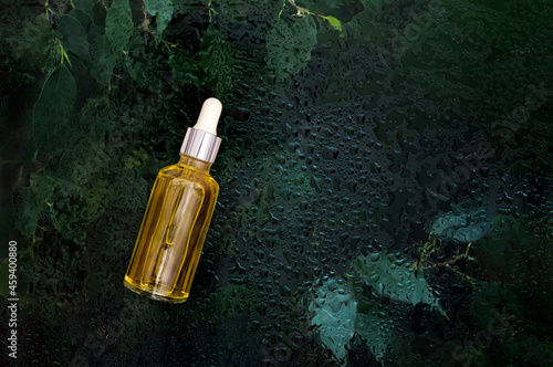 cosmetic serum bottle on natural background with water drops organic cosmetics