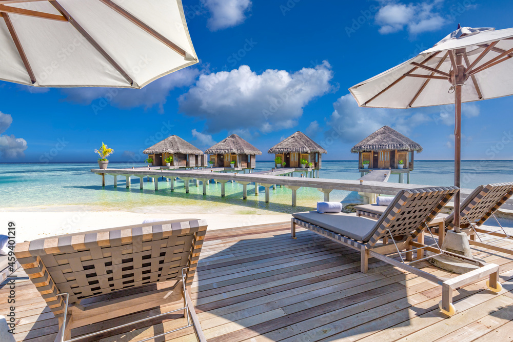 Luxury hotel with water villas, palm tree leaves over white sand, close to blue sea seaside shore. Beach chairs, beds white umbrellas. Summer vacation and holiday, couple beach resort tropical island