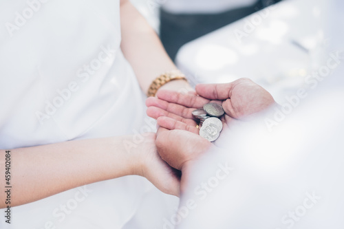 Groom palms holding the Unity Coins known as Las Arras or Arrhae over the bride's palms during the wedding ceremony. Selective focus. Copy space.