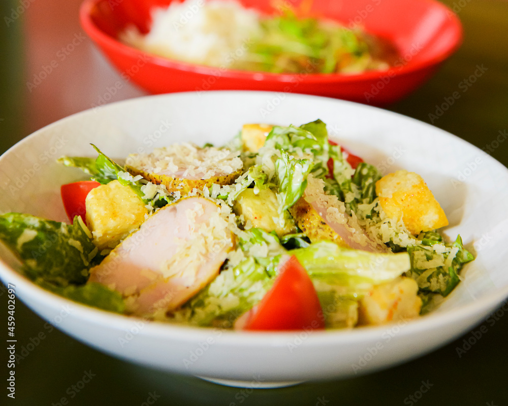 Caesar Salad served in a white bowl on the table in restaurant or diner. Traditional recipe of Caesar salad Caesar Salad served in a white bowl on the table in restaurant or diner. Traditional recipe of Caesar salad