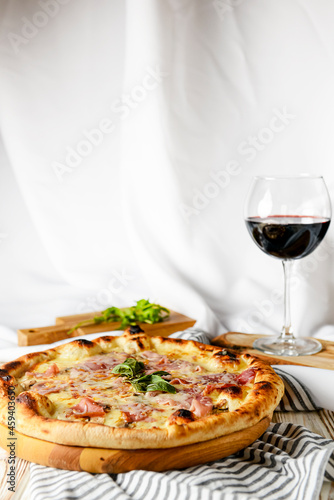 Glass of red wine with pizza on cutting board on rustic wooden table. Italian cuisine concept