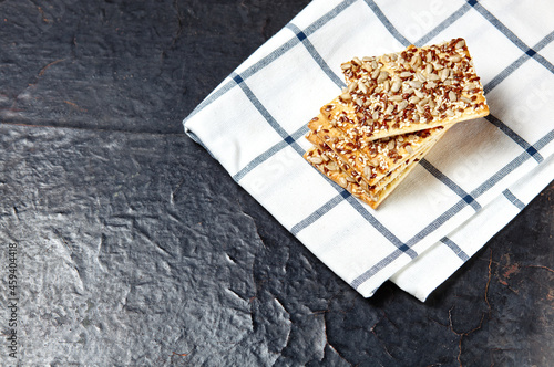 Crisp bread with seeds. Crunchy crispbread on a wooden background. Healthy snack: cereal crunchy multigrain cereal flax seed, sunflower seeds protein bread bar