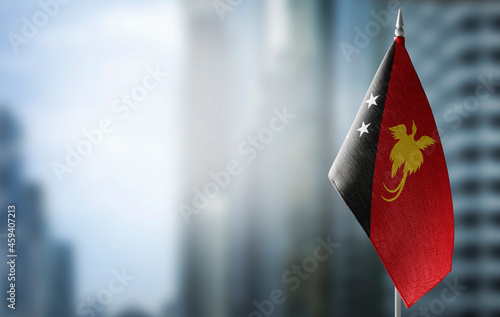 A small flag of Papua New Guinea on the background of a blurred background